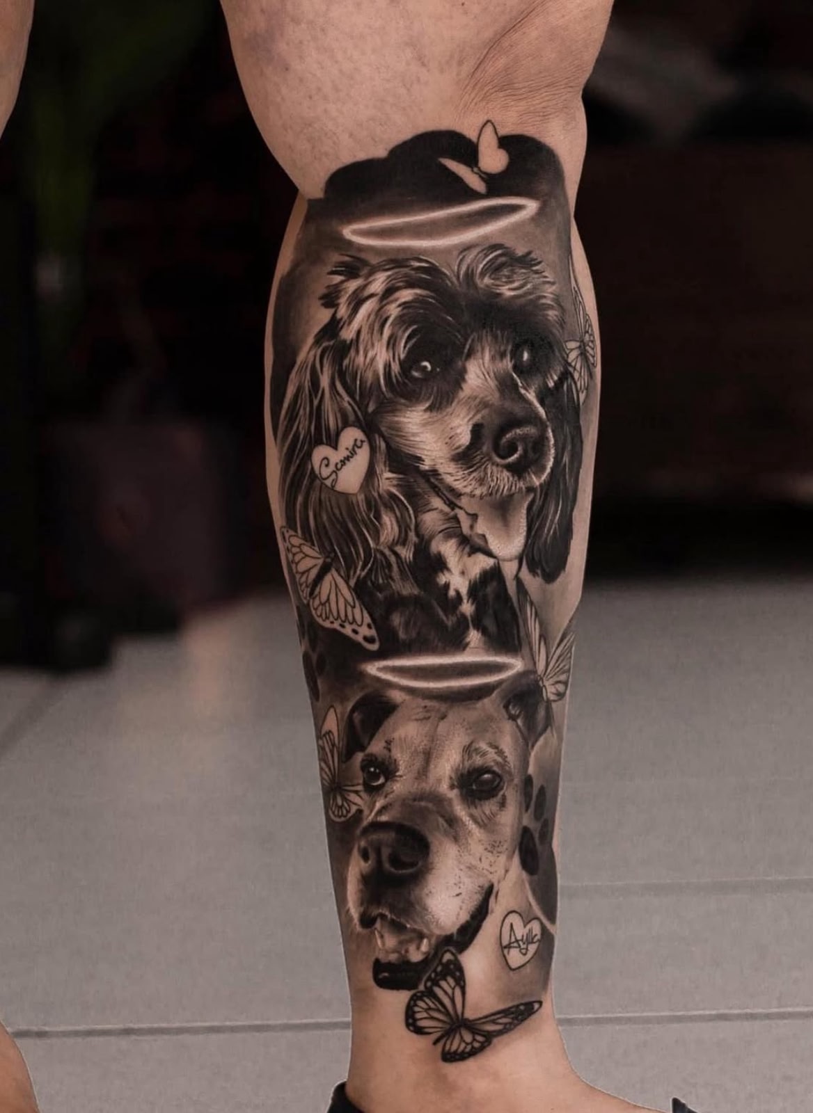 Panturrilha com retrato memorial de dois cães com auréolas e borboletas, realismo em preto e cinza por Felipe Carlos.
